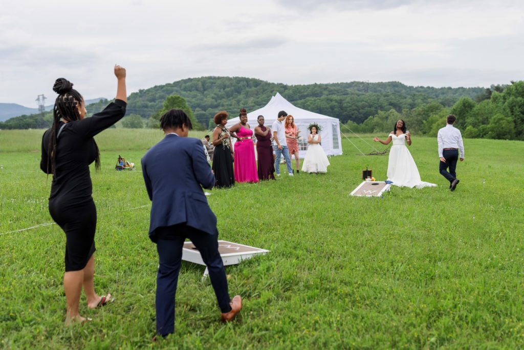 wedding guests having fun and celebrating playing corn hole with bridal couple