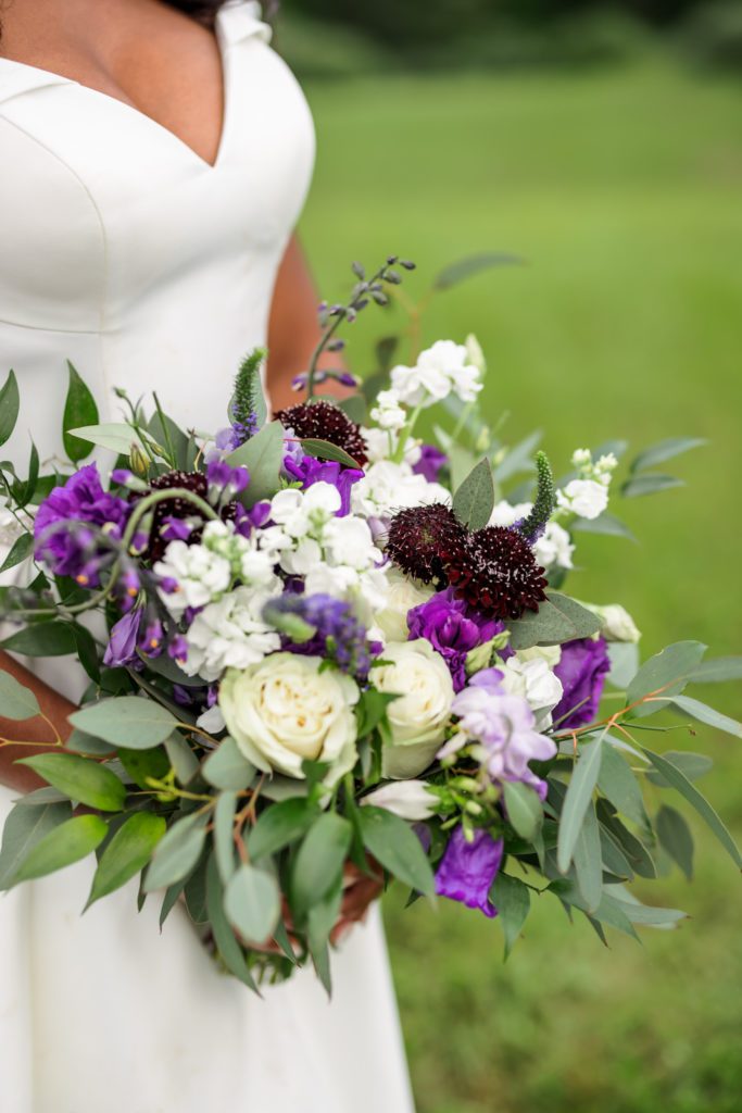 white and purple bridal bouquet being held by bride