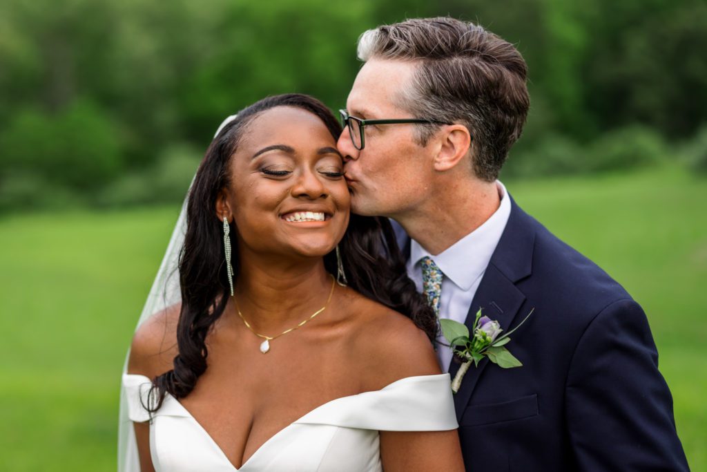 groom kissing bride's cheek during wedding portraits
