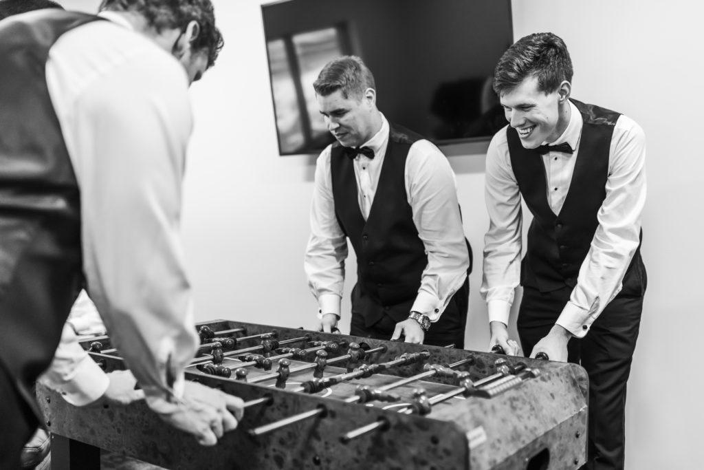 groom and groomsmen playing fooseball before wedding 