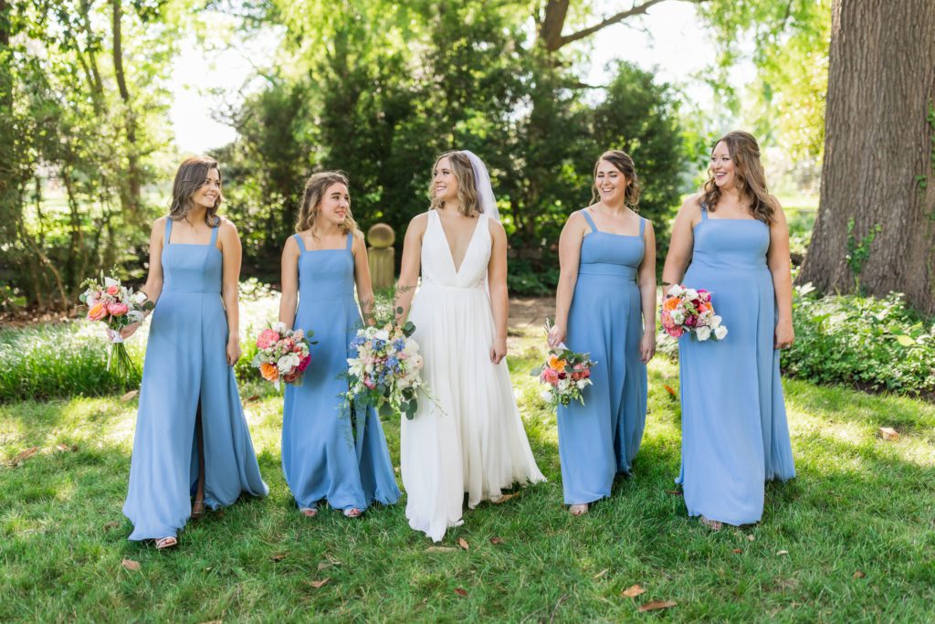 bride walking with bridesmaids wearing blue dresses 