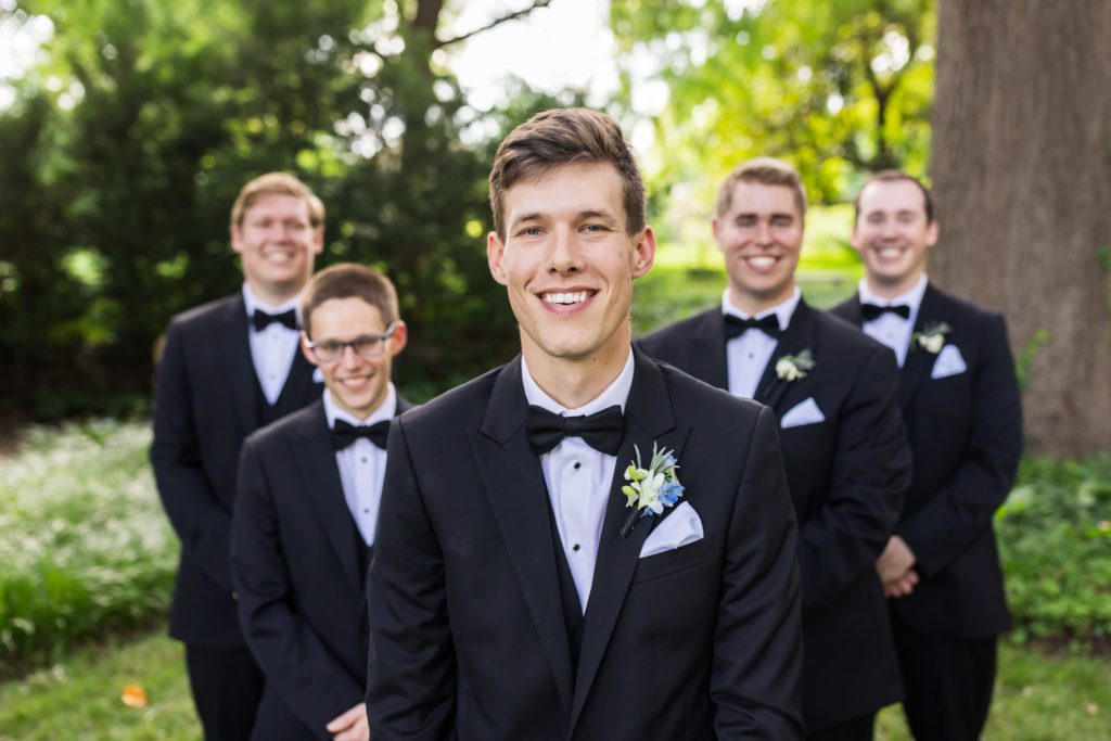 groom standing in front with groomsmen behind him wearing tuxedos