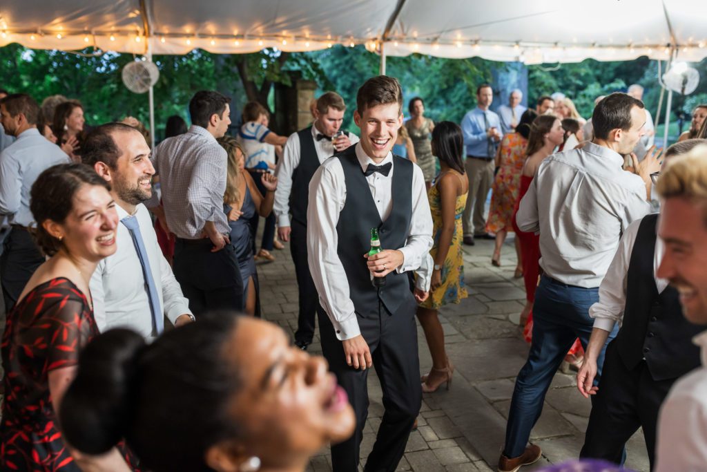 groom having fun with wedding guests at summer virginia house reception