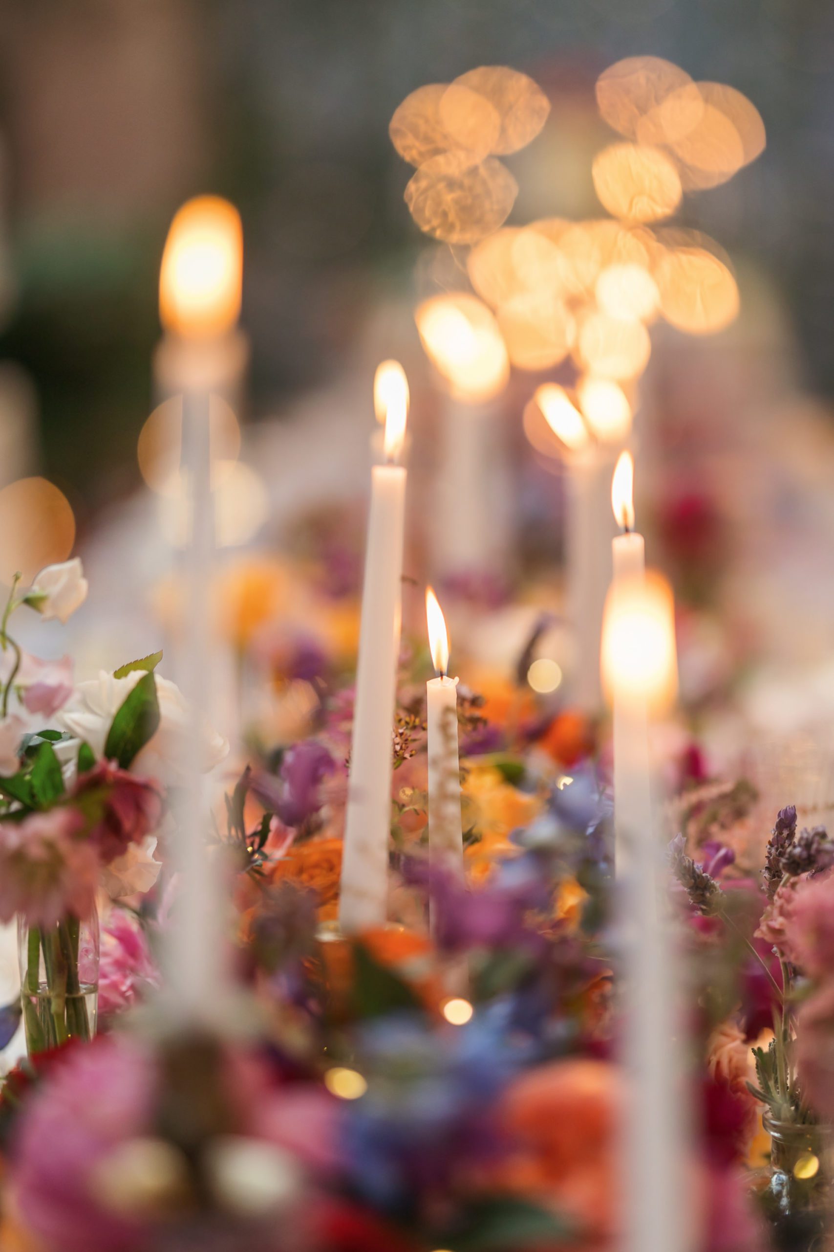 close up of tall candlesticks surrounded by floral centerpiece