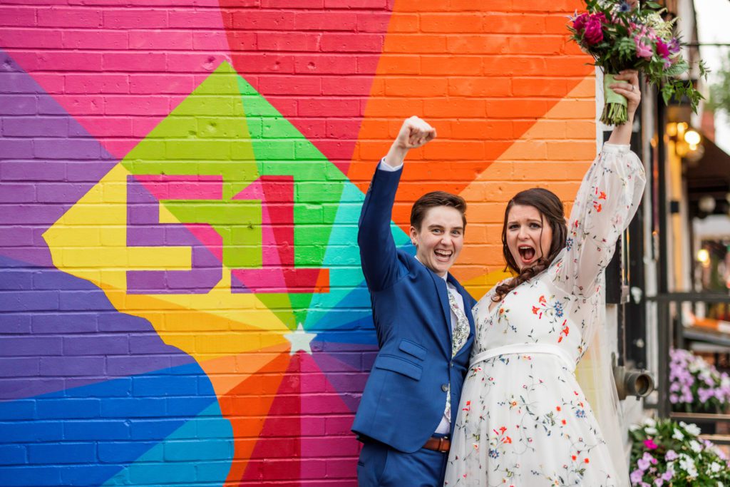 couple cheering in front of colorful mural in DC