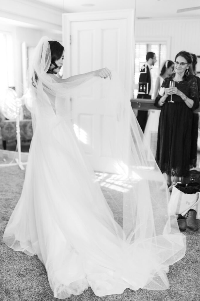 bride lifting veil in air while wearing wedding dress before wedding