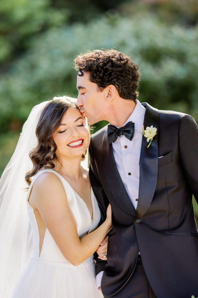 groom kissing bride on forehead on wedding day