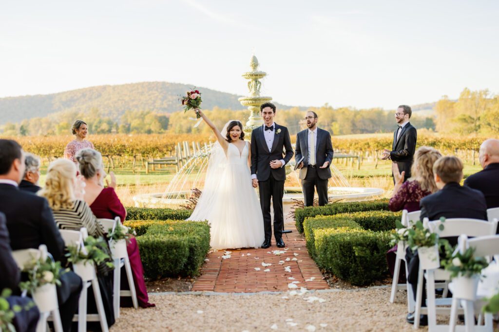 bride and groom celebrating recent marriage while bride lifts bouquet in the air