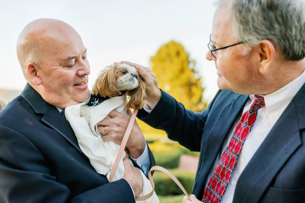 man holding dog while other man pets dog