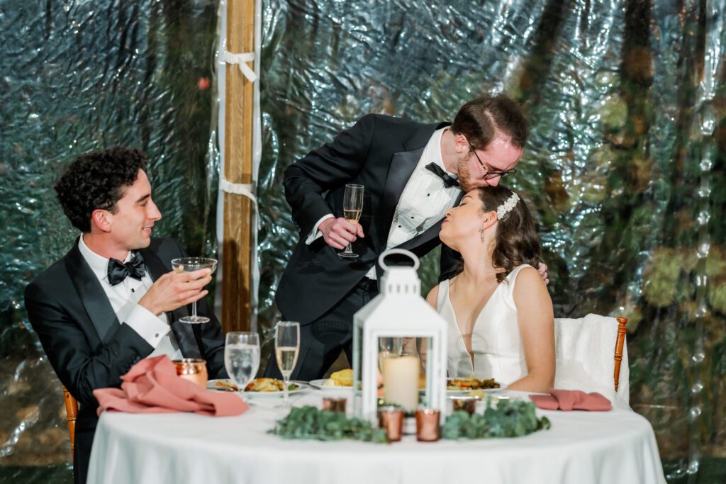 groomsmen kissing bride on top of head after toast