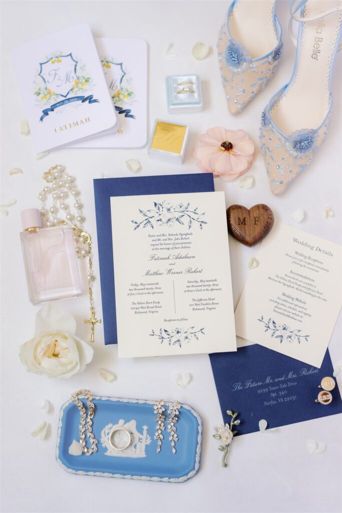 Close up of invitations and wedding details with bridal shoes, flowers and vow books