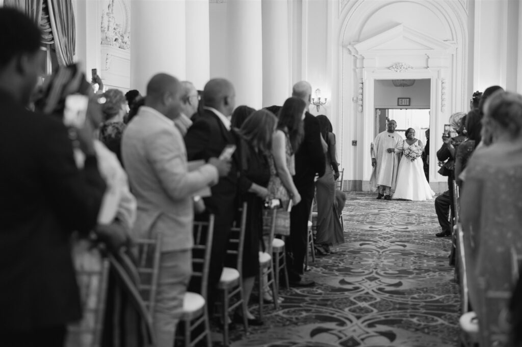 Black and white photo of bride walking down the aisle with her father