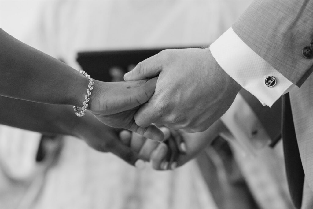 Black and white photo of bride and groom holding hands