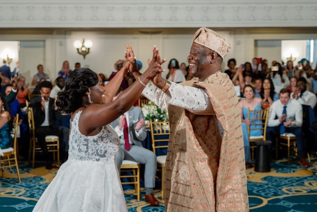 Bride dancing with father during father daughter dance with hands in the air