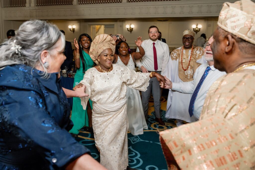 Bride's parents and groom's parents hold hands and dance in a circle to celebrate