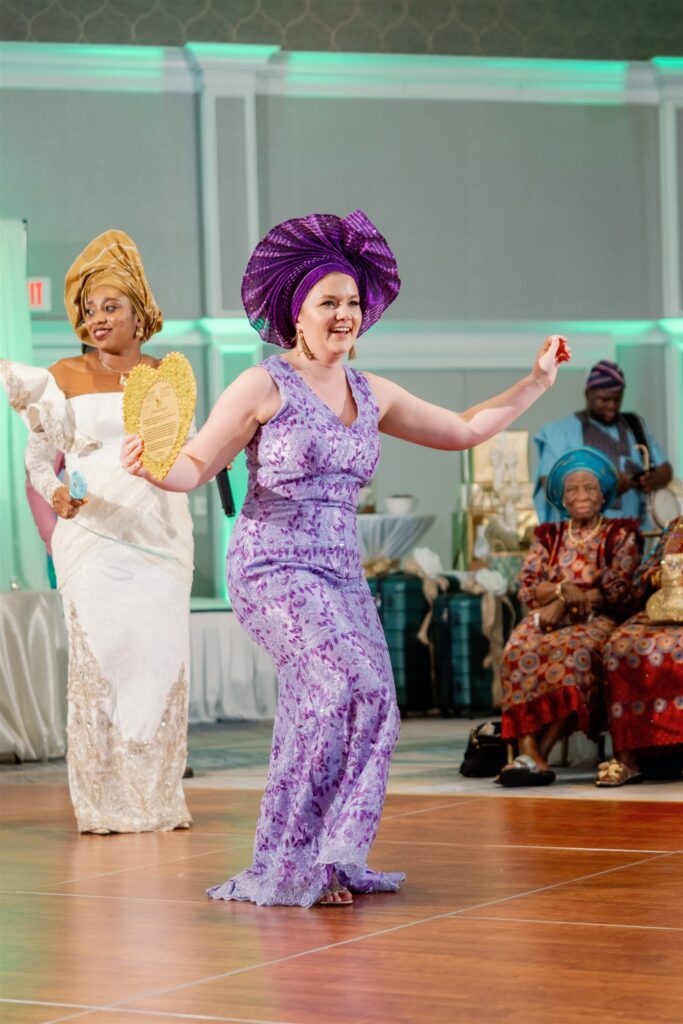 Women dancing while holding gold heart and wearing purple headpiece