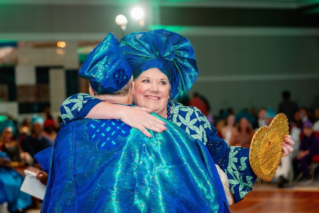 Woman embracing man while wearing blue traditional Nigerian clothing while wearing gold heart