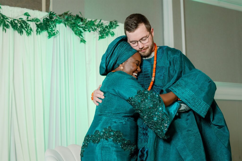 Bride and groom hugging while wearing green clothing during Nigerian-American Wedding reception