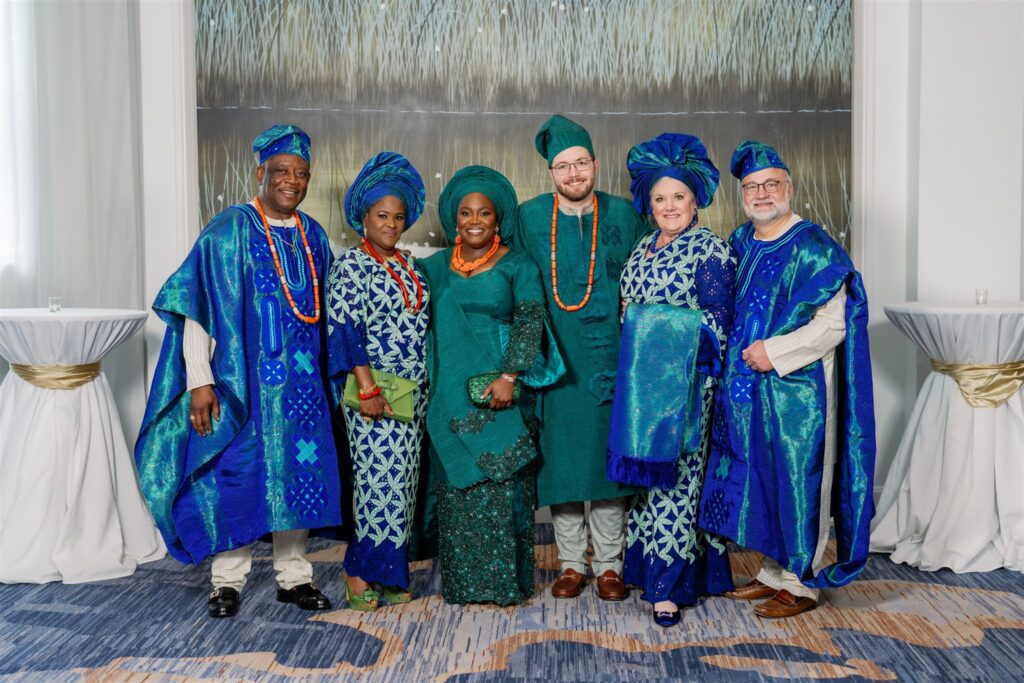 Bride and groom smiling while standing with both sets of parents