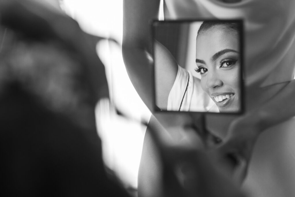 bride looking at herself in mirror to see hair and makeup finished looks