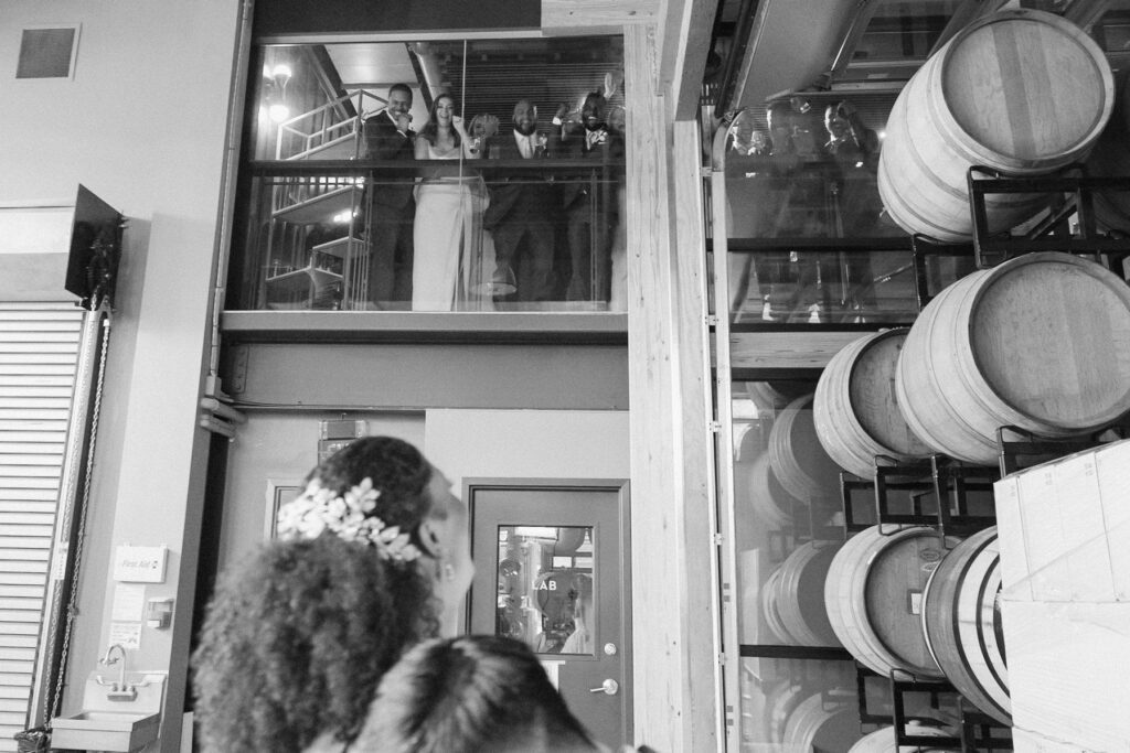Bride looking up and laughing while seeing wedding party watching first look