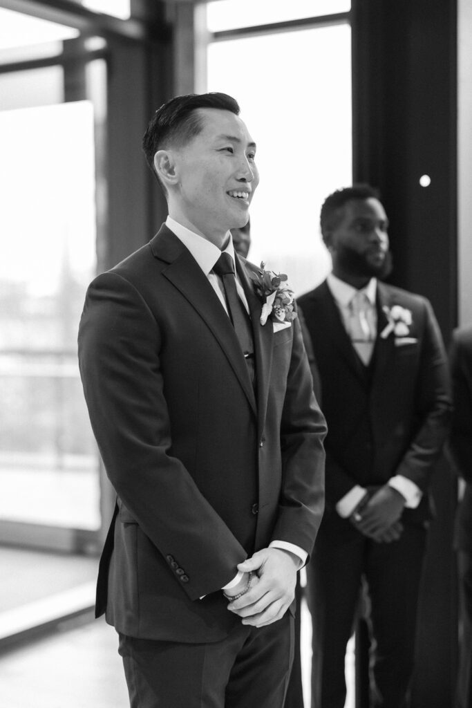 Groom standing at alter watching his bride walk down the aisle