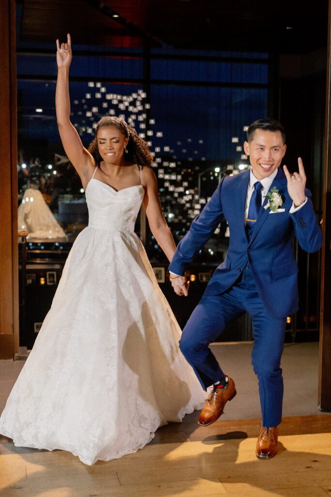 Bride and groom enter reception making rock on symbol