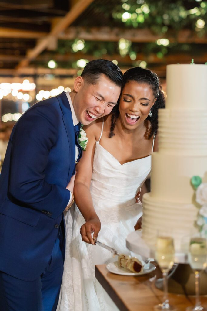 Couple laughing before they begin cutting their wedding cake