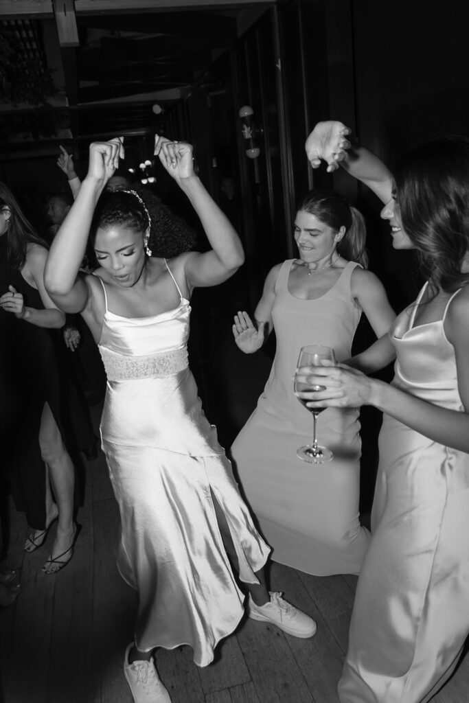 Bride with hands in air dancing with friends